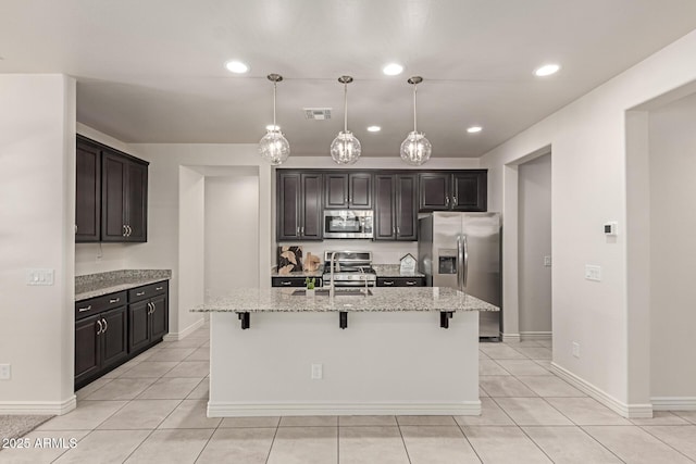 kitchen with a kitchen breakfast bar, a center island with sink, and stainless steel appliances