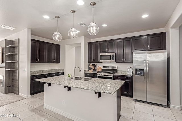 kitchen featuring a breakfast bar area, stainless steel appliances, an island with sink, and sink