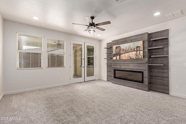 unfurnished living room featuring carpet, ceiling fan, a fireplace, and french doors