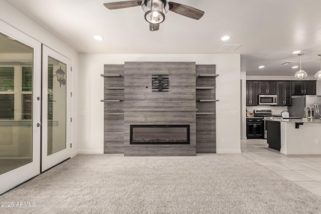 unfurnished living room with light carpet, ceiling fan, a fireplace, and french doors