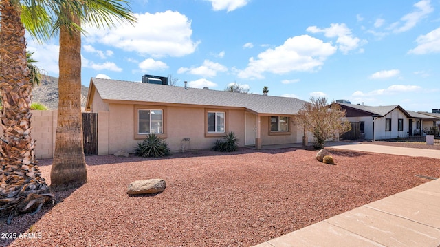 ranch-style house featuring stucco siding, driveway, roof with shingles, and fence