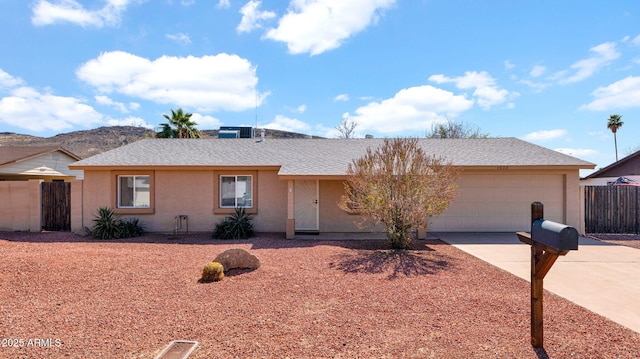 ranch-style home with fence, concrete driveway, roof with shingles, stucco siding, and a garage