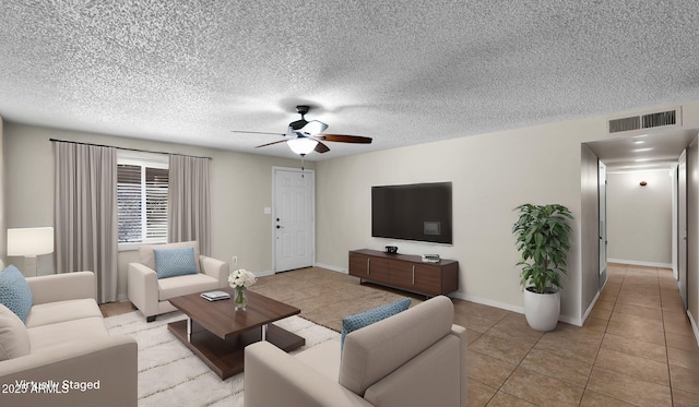 living area featuring light tile patterned floors, baseboards, visible vents, ceiling fan, and a textured ceiling