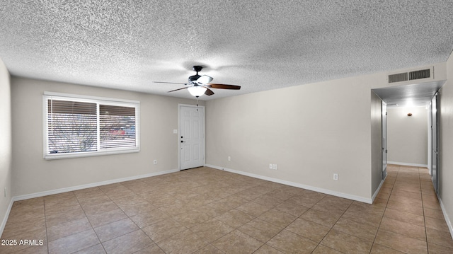 empty room with visible vents, baseboards, a textured ceiling, and a ceiling fan
