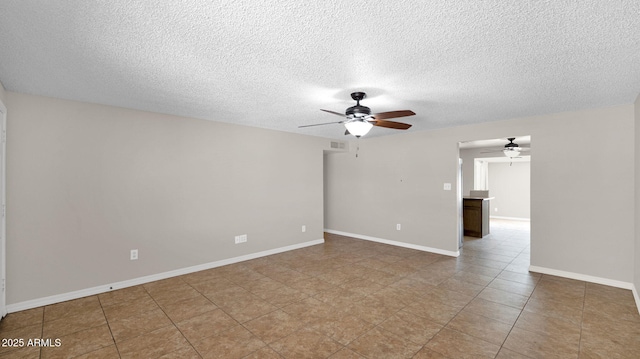 empty room with visible vents, a ceiling fan, baseboards, and a textured ceiling