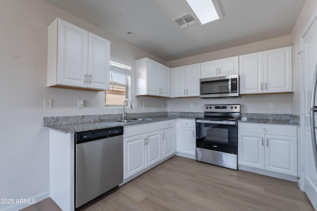 359 E Watson Pl, Casa Grande, AZ 85122 - kitchen with appliances with stainless steel finishes, a sink, white cabinetry, and light wood finished floors