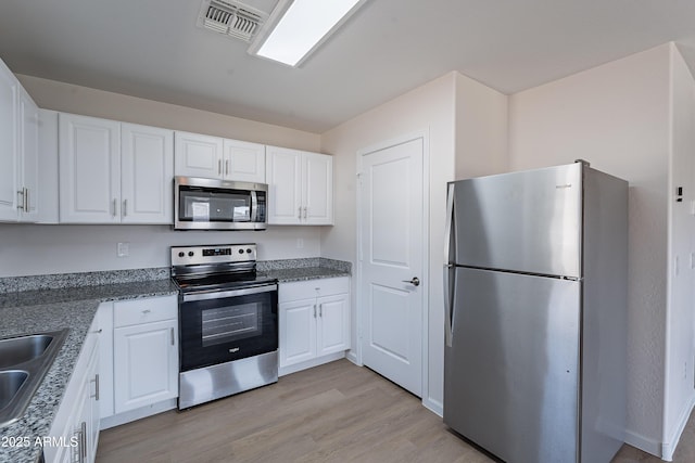 359 E Watson Pl, Casa Grande, AZ 85122 - kitchen with appliances with stainless steel finishes, light wood-type flooring, white cabinetry, a sink, and stone countertops
