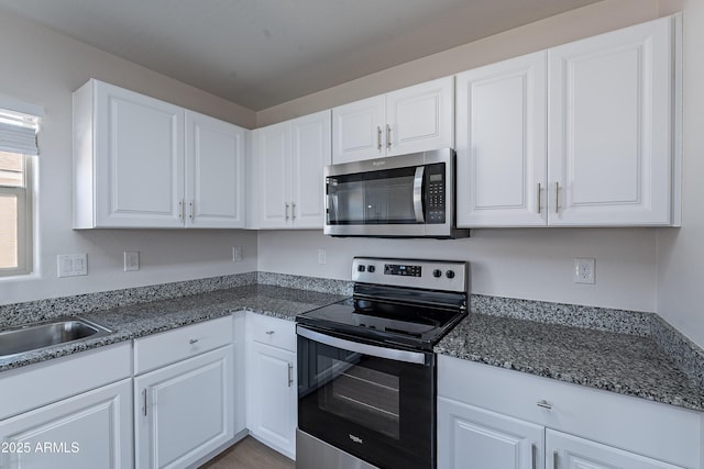359 E Watson Pl, Casa Grande, AZ 85122 - kitchen with stainless steel appliances, white cabinets, a sink, and dark stone counters