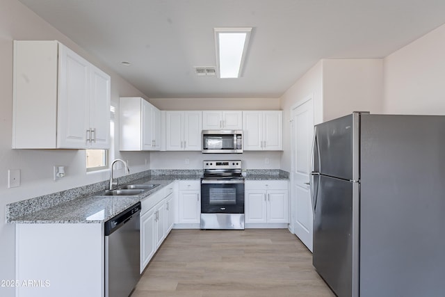 359 E Watson Pl, Casa Grande, AZ 85122 - kitchen featuring appliances with stainless steel finishes, a sink, light wood-style floors, white cabinetry, and light stone countertops