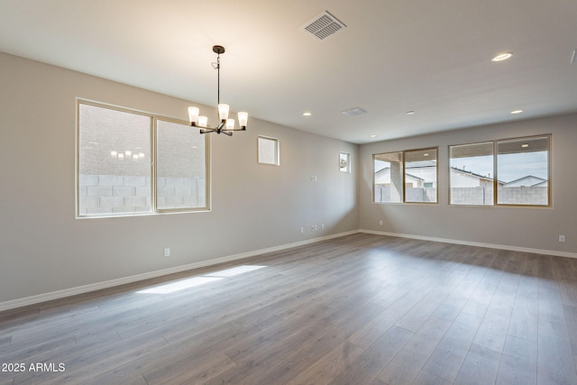 empty room with a wealth of natural light, visible vents, baseboards, and an inviting chandelier