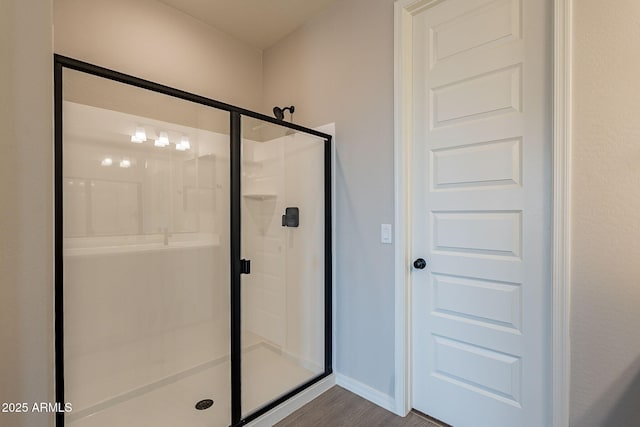 bathroom with baseboards, a stall shower, and wood finished floors