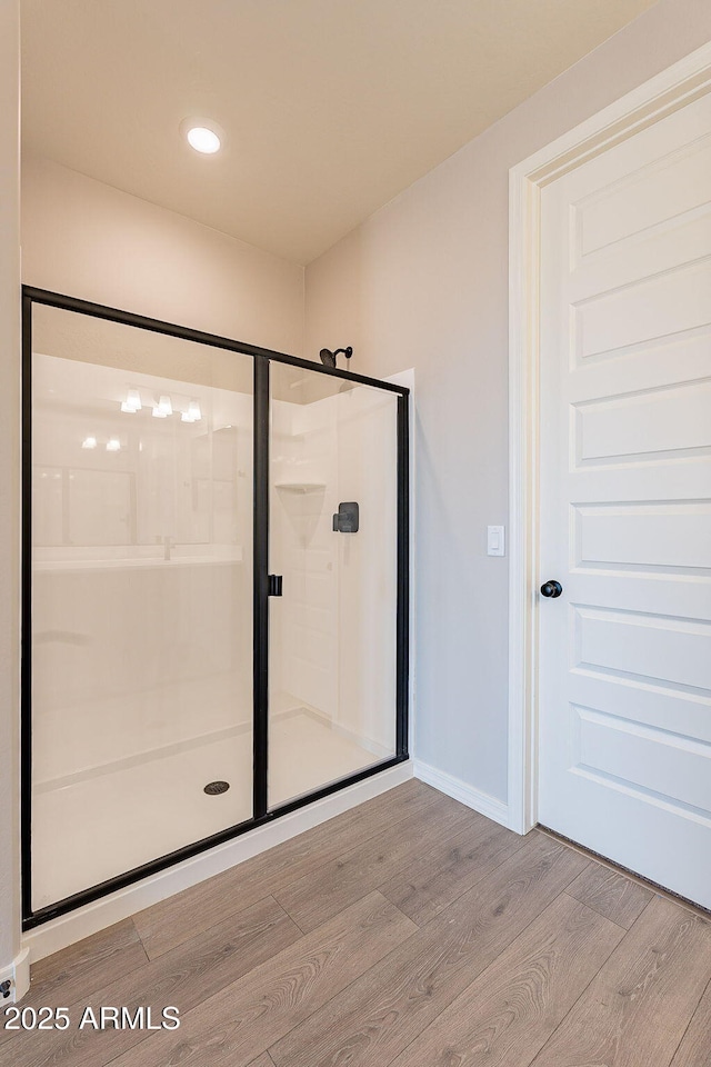 full bath featuring a shower stall, wood finished floors, baseboards, and recessed lighting
