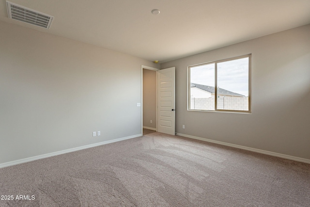 carpeted spare room featuring visible vents and baseboards