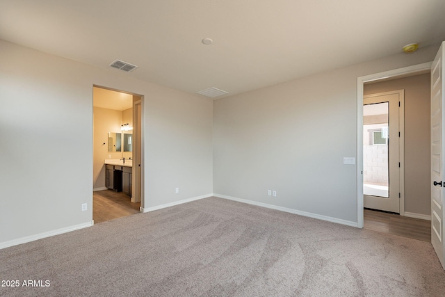 unfurnished bedroom with light carpet, a sink, baseboards, and visible vents