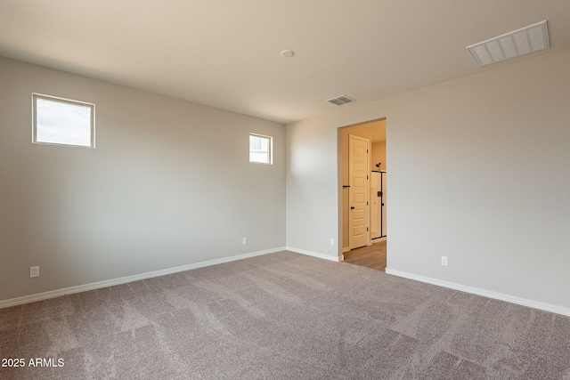 carpeted spare room featuring visible vents and baseboards