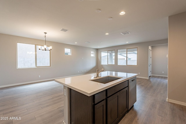 kitchen with visible vents, a sink, open floor plan, light countertops, and stainless steel dishwasher