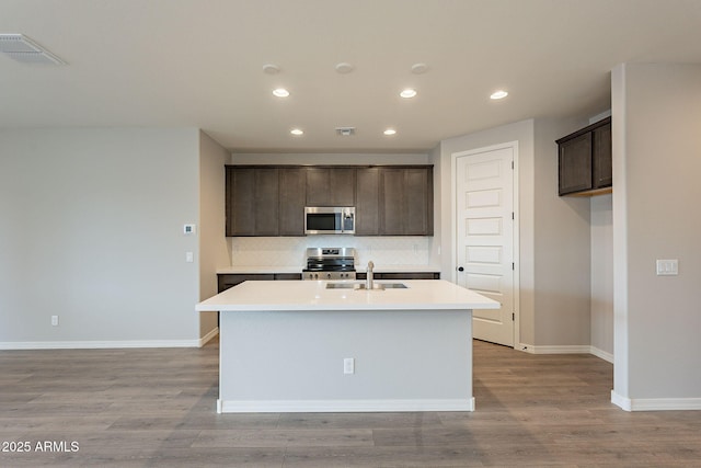 kitchen with tasteful backsplash, recessed lighting, a center island with sink, stainless steel appliances, and a sink