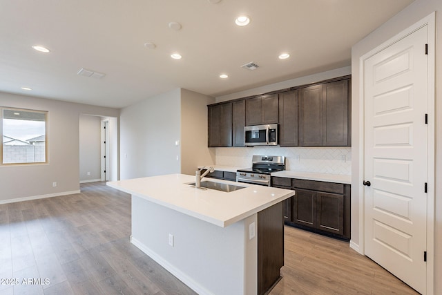 kitchen featuring appliances with stainless steel finishes, a sink, visible vents, and dark brown cabinetry
