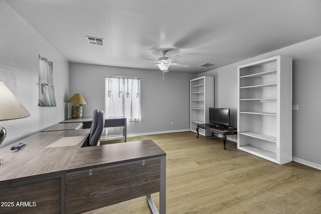 office area with visible vents, a ceiling fan, baseboards, and wood finished floors
