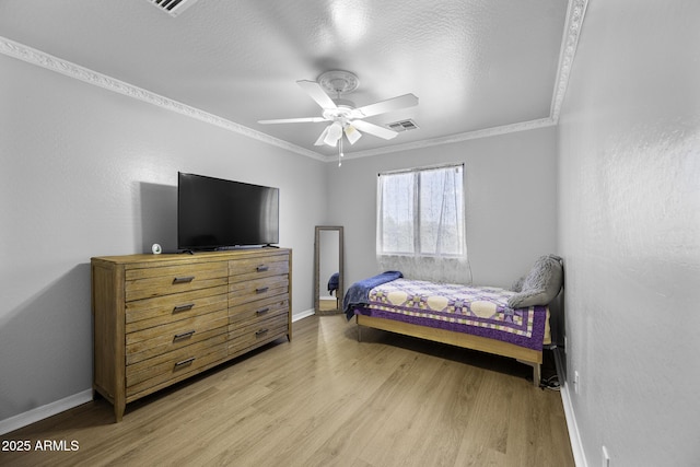 bedroom featuring baseboards, ornamental molding, light wood finished floors, and visible vents