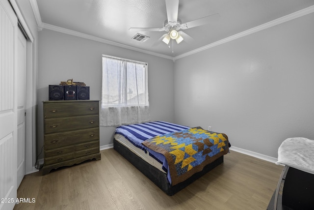 bedroom featuring visible vents, ornamental molding, wood finished floors, baseboards, and a ceiling fan