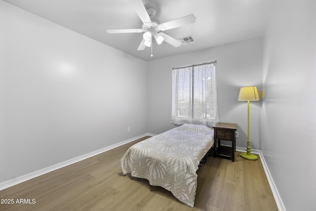 bedroom featuring visible vents, a ceiling fan, baseboards, and wood finished floors