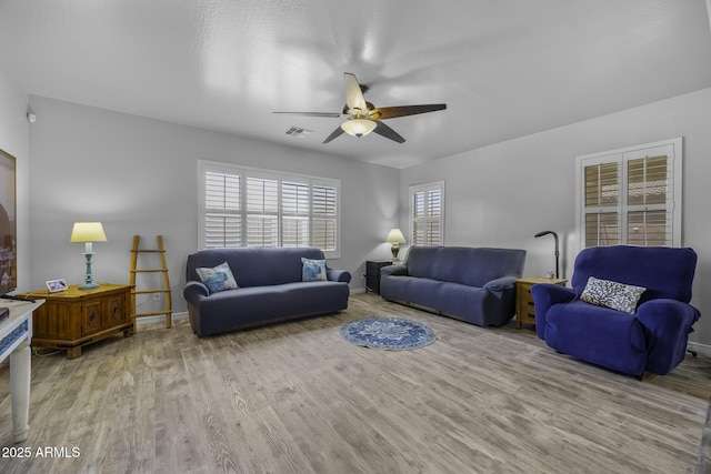 living room featuring baseboards, ceiling fan, wood finished floors, and visible vents
