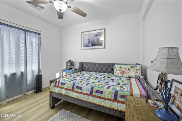 bedroom with visible vents, a ceiling fan, baseboards, and wood finished floors