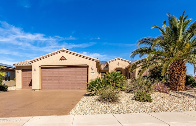 mediterranean / spanish-style home with driveway, an attached garage, a tile roof, and stucco siding