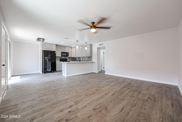 unfurnished living room featuring ceiling fan, light wood finished floors, a sink, and visible vents