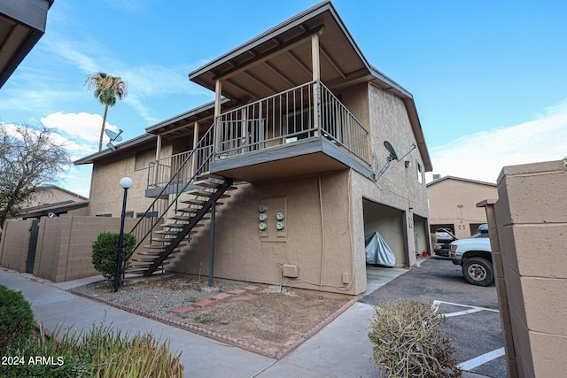 view of front facade featuring a garage, stairs, fence, and stucco siding