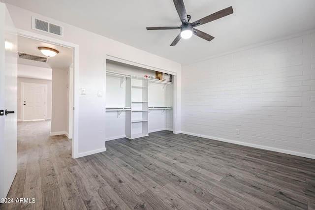 unfurnished bedroom featuring brick wall, wood finished floors, and visible vents