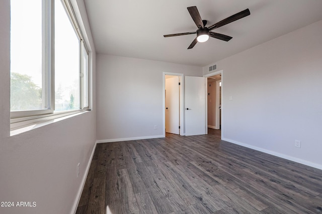 unfurnished bedroom with dark wood-type flooring, a ceiling fan, visible vents, and baseboards