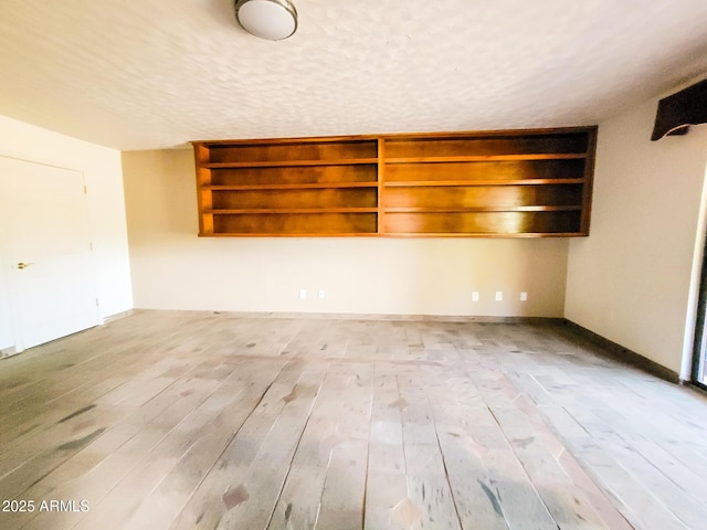 unfurnished room with light hardwood / wood-style floors and a textured ceiling