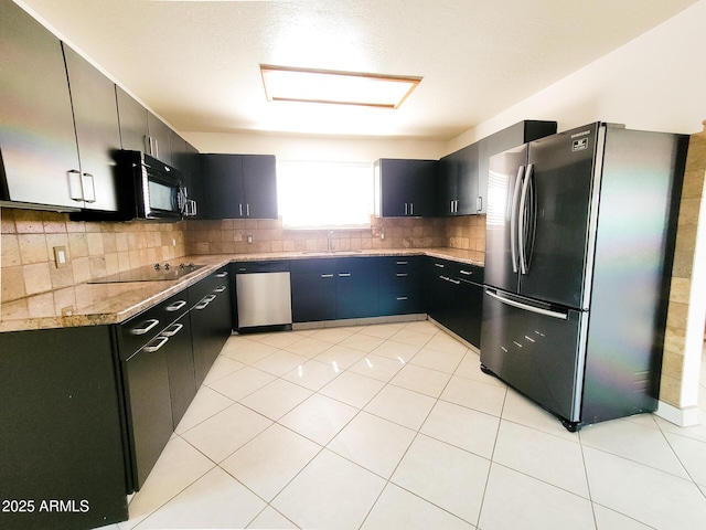 kitchen with black appliances, sink, backsplash, light tile patterned flooring, and light stone counters