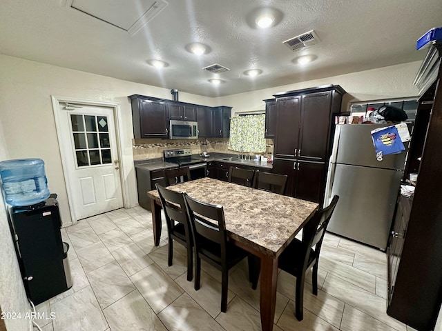 kitchen featuring a textured ceiling, sink, appliances with stainless steel finishes, and tasteful backsplash