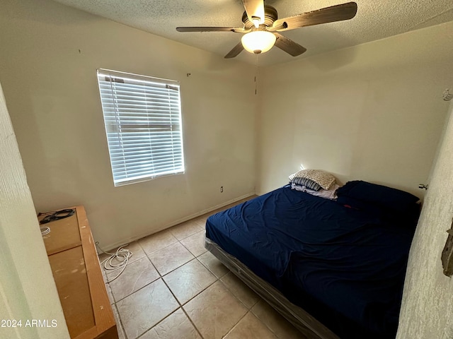 tiled bedroom with ceiling fan and a textured ceiling