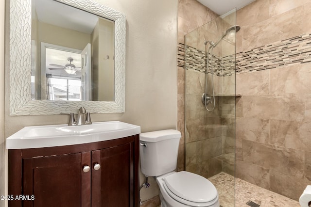 bathroom featuring toilet, vanity, ceiling fan, and tiled shower