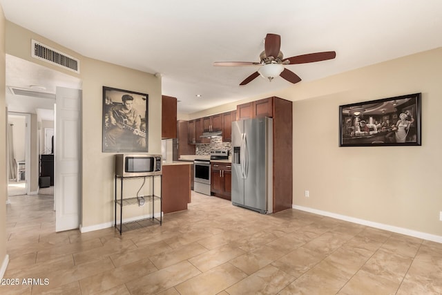 kitchen with appliances with stainless steel finishes, ceiling fan, a kitchen bar, and backsplash