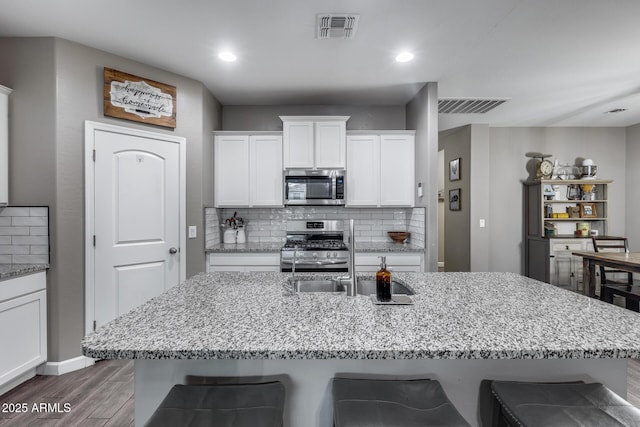 13657 W Paso Trl, Peoria, AZ 85383 - kitchen with appliances with stainless steel finishes, a breakfast bar, wood finished floors, light stone countertops, and white cabinets
