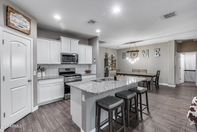 13657 W Paso Trl, Peoria, AZ 85383 - kitchen with appliances with stainless steel finishes, wood finished floors, a sink, baseboards, and backsplash