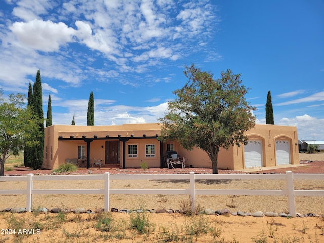 adobe home featuring a garage, a fenced front yard, and stucco siding