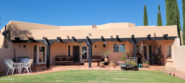 rear view of house with a lawn, a patio, a ceiling fan, and stucco siding