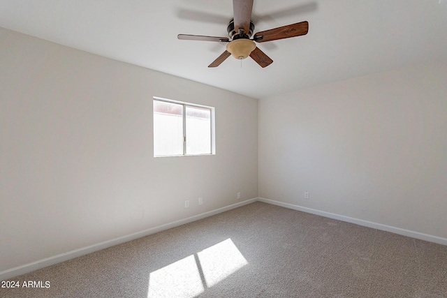 carpeted spare room featuring ceiling fan and baseboards