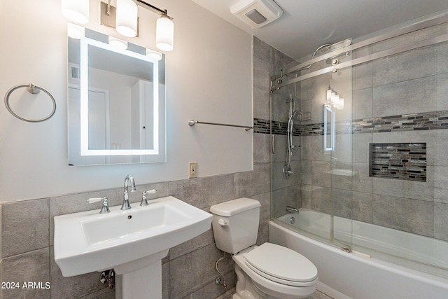 bathroom with visible vents, tile walls, toilet, a sink, and shower / bathing tub combination