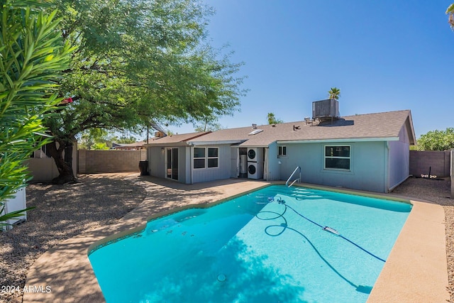 rear view of property featuring cooling unit, a patio area, a fenced backyard, and stacked washer / drying machine