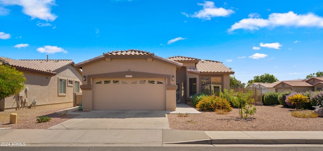 mediterranean / spanish-style home featuring a garage, concrete driveway, a tiled roof, and stucco siding