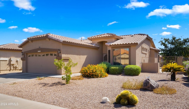 mediterranean / spanish house featuring a garage, driveway, a tiled roof, and stucco siding