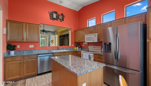 kitchen with brown cabinetry, stainless steel appliances, a sink, and a center island