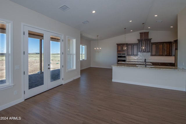 kitchen with sink, dark brown cabinetry, light stone counters, stainless steel double oven, and french doors